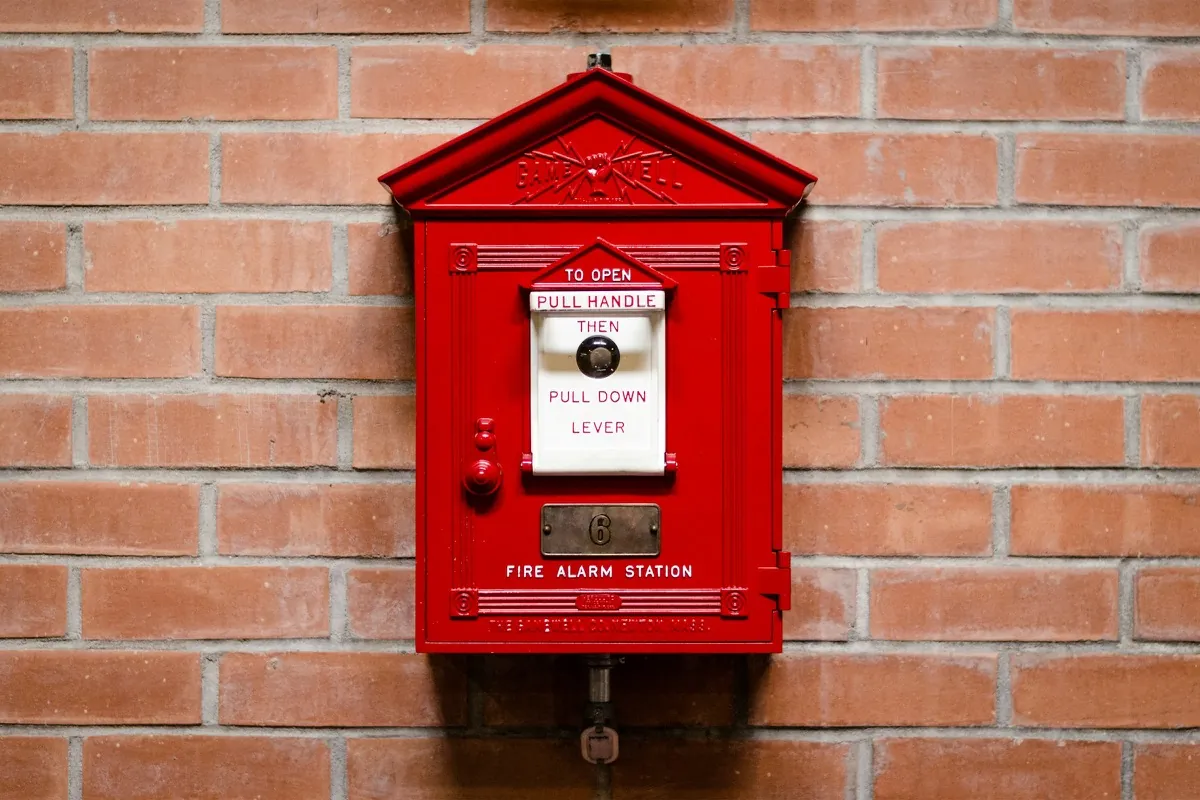 Red manual fire alarm call point mounted on a building wall