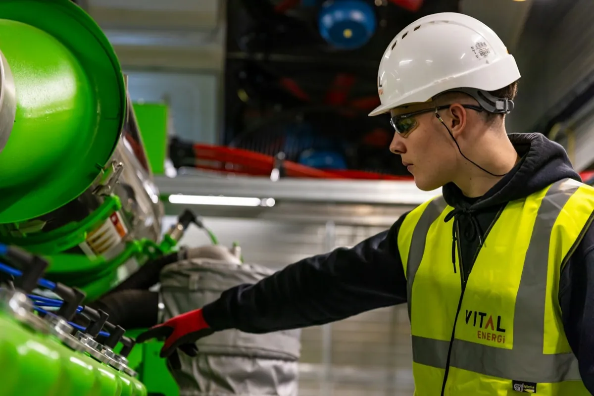 Technician in hard hat and hi-vis vest working on plant equipment on site