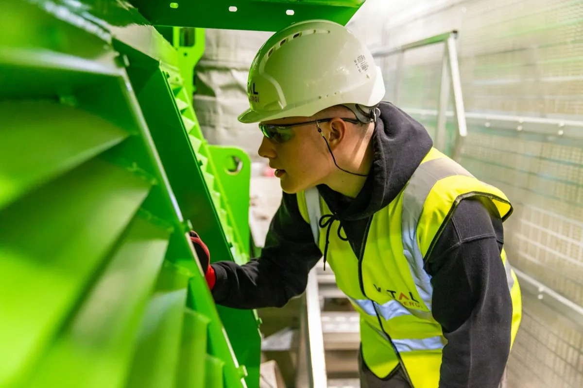 Technician in hard hat and hi-vis inspecting plant equipment