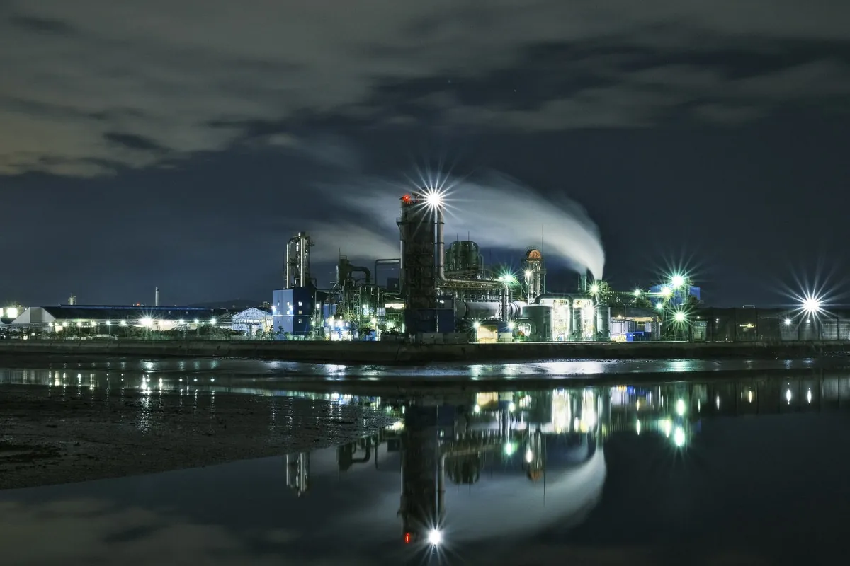Industrial plant illuminated at night beside water